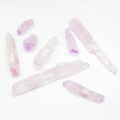 Different sized pieces of natural raw pink Kunzite crystal gemstone randomly arranged on white background
