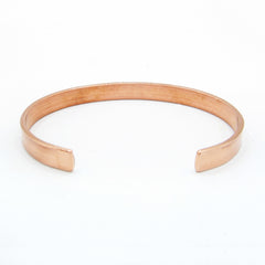 View of inside/backside of a narrow plain polished copper open cuff bracelet on white background