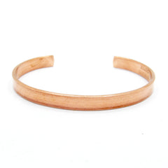 Front view of a narrow plain polished copper open cuff bracelet on white background