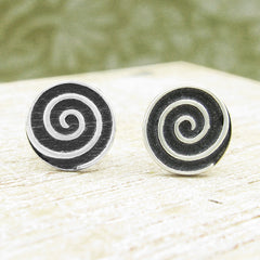 View of face of pair of 925 sterling silver spiral stud earrings black and silver on wood and green background