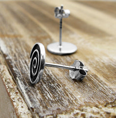Side view of pair of 925 sterling silver spiral stud earrings black and silver on wood background
