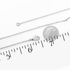 A silver chain necklace with a lobster clasp, shown alongside a US dime for scale and a black ruler with inch markings on a white background.