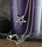 Tiny Second Degree Inverted Pentagram Pendant Necklace Wiccan Wicca Pentacle Witchy Jewelry Goth Gothic Halloween Baphomet Satan on a necklace hanging from purple candle
