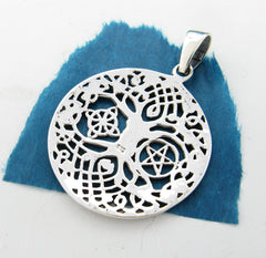 View of back side of cut-out Tree of Life pendant on ripped green paper with white background.