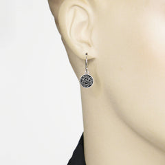 Silver earrings with an intricate Celtic design on an ear mannequin.