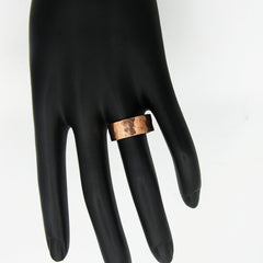 Gently hammered pure copper band ring displayed on black mannequin's hand with white background.