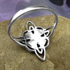 View of reverse side of fancy silver Witch's Knot ring on brown stone background