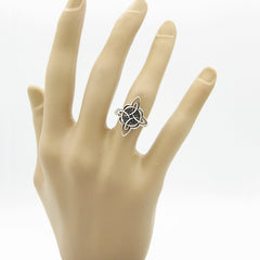 Fancy silver Witch's Knot ring on worn of mannequin's hand against white background