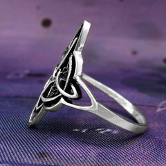 Side view of fancy silver Witch's Knot ring on purple  cloth background