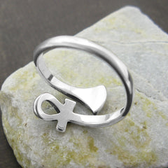 Inside/back view of silver wraparound ring with ancient Egyptian Ankh symbol design sitting on flat light-colored stone against dark brown background.
