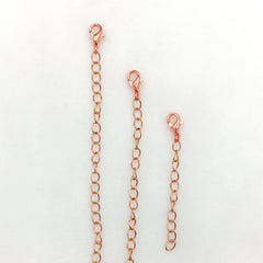 Three copper chain extension links of different lengths with lobster clamps, arranged vertically on a plain white background.