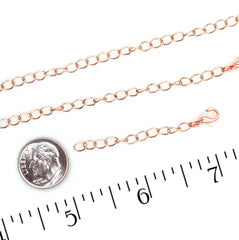 copper chain links shown on a white background with a silver coin and ruler for scale.