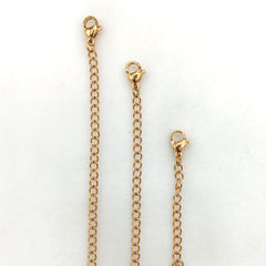 Three gold chain extender straps with lobster clasp ends, displayed vertically on a plain white background.