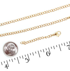 A gold chain necklace with a lobster clasp and extender link, displayed on a white background with a US dime for scale and a black inch ruler at the bottom.