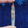 long clear copper wire wrapped quartz crystal with spiral designs against a dark blue background