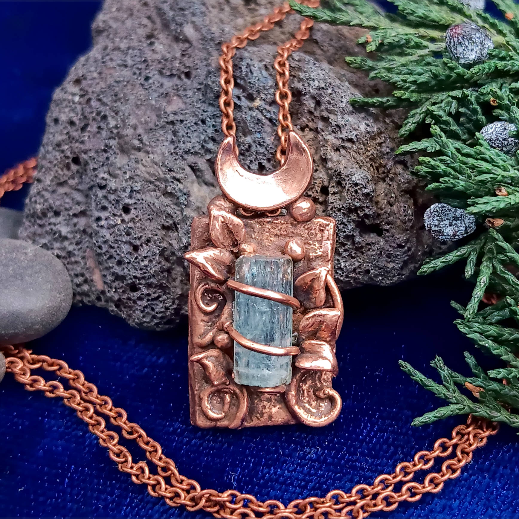 Copper pendant with raw blue aquamarine on a chain against a natural background
