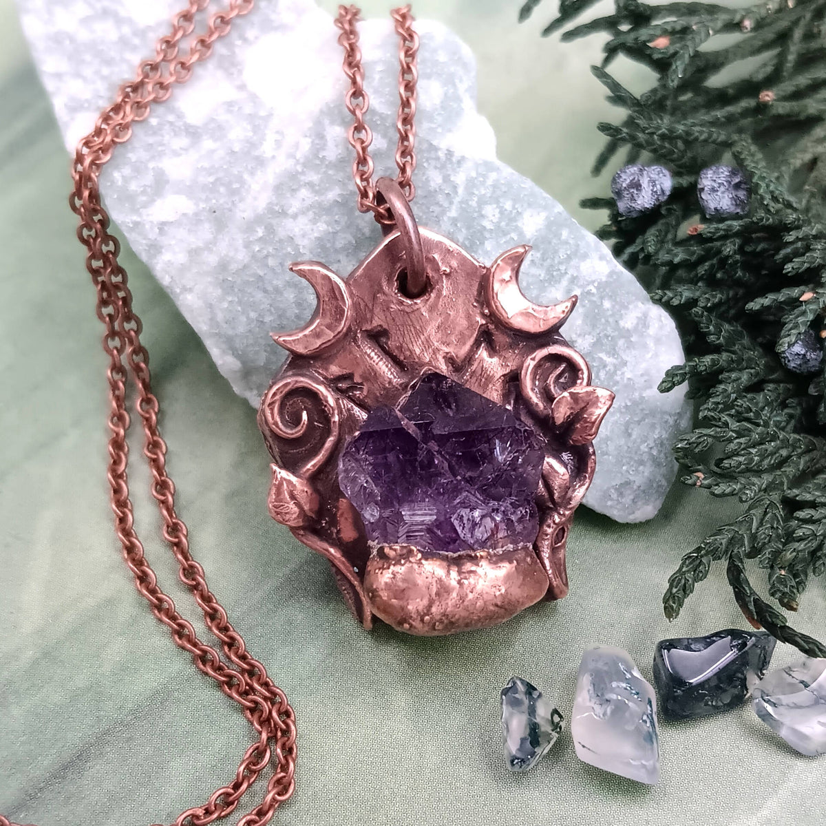 Raw Tanzanian Amethyst Crystal Rune Copper Necklace, Electroformed Pendant on green background with plants and pebbles