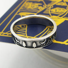Oxidized sterling silver band type ring with trees and moon design displayed on a dark blue Tarot card with gold graphics on a white background.