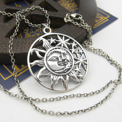 Cut-out sterling silver pendant with sun moon and stars design and chain on half dark half white  background