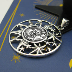 Side view of cut-out sterling silver pendant with sun moon and stars design on blue background