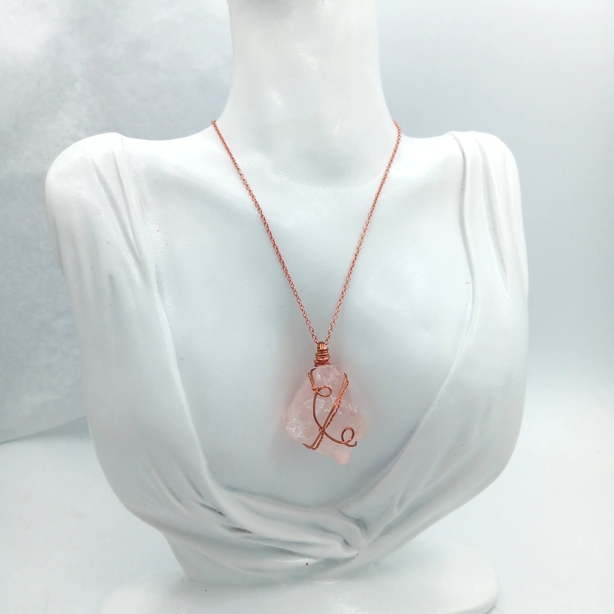 Necklace with a pink rose quartz pendant on a mannequin bust against a white background