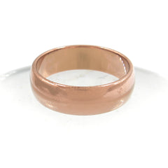 Slightly overhead view of plain domed copper ring resting with a white background.