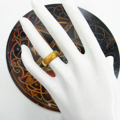 Front view of plain domed copper ring displayed on a white mannequin's hand with a round black and copper-colored graphic in the background.
