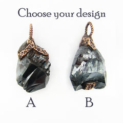 Two raw hematite crystal pendant options labeled A and B with the text 'Choose your design' above, on a plain white background. The pendants have dark gray to black stones with copper-colored metal caps and loops.