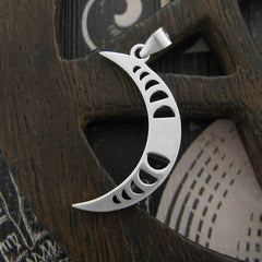 Back side of a sterling silver pendant in shape of crescent moon with a cut-out moon-phases design on a dark wooden pentagram prop on weathered black wooden surface with white graphics.