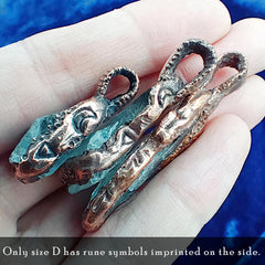 Copper and aquamarine pendant charms with engraved rune-like symbols and loop tops, resting on a person's fingers against a blue fabric background. Text at the bottom reads, 'Only size D has rune symbols imprinted on the side.
